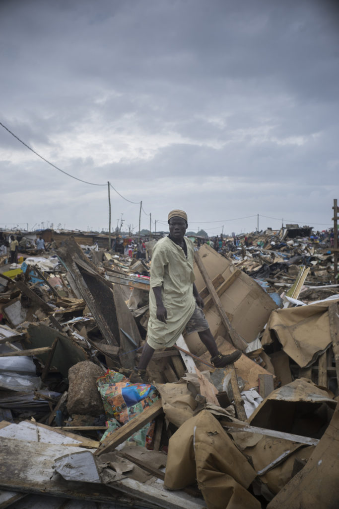 Mohammed stood atop his demolished home. In June, the Accra Metropolitan Assembly (AMA) brought bulldozers into Old Fadama to widen and dredge the waterways that surround the slum. The residents had been warned of an impending demolition since January, but recent and dangerous flooding spurred a more aggressive demolition. Over 20,000 people were evicted from the shoulders of the Odaw River and the Korle Lagoon. Mohammed built his home by hand three years ago.