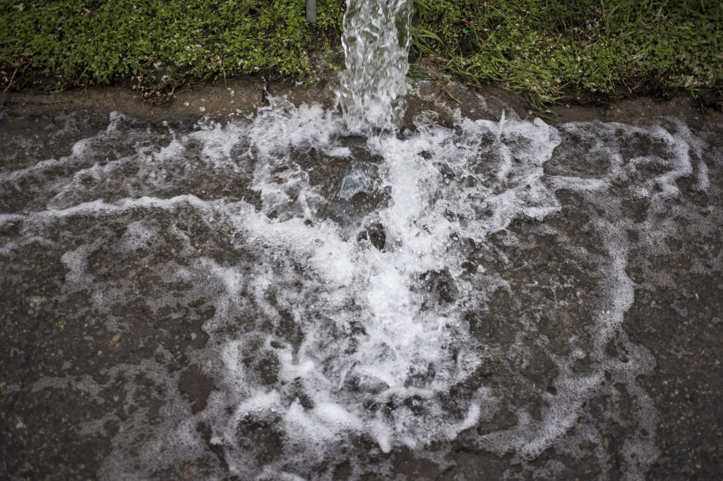 Water gushes from a fire hydrant along Harrison Street as part of a system maintenance program with the Flint Water Department thought to clear out potential contaminants from the water mains on Tuesday, May 12, 2015. (Brittany Greeson/GroundTruth)