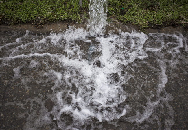 Water gushes from a fire hydrant along Harrison Street as part of a system maintenance program with the Flint Water Department thought to clear out potential contaminants from the water mains on Tuesday, May 12, 2015. (Brittany Greeson/GroundTruth)