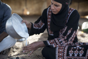 Um Hussein al-Mazana mixes fresh camel milk into a glass of traditional Bedouin tea in Jordan's Wadi Rum desert on August 6, 2015.