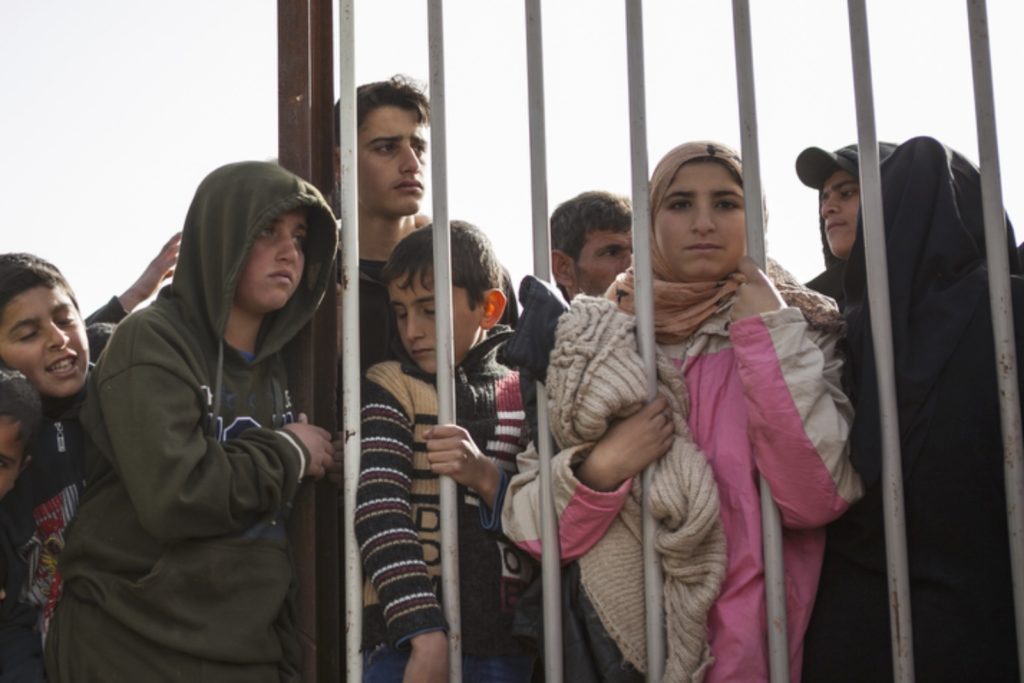 Children peer through the fence during distribution hours in Zaatari refugee camp on January 18, 2016. (Christopher Lee/GroundTruth)