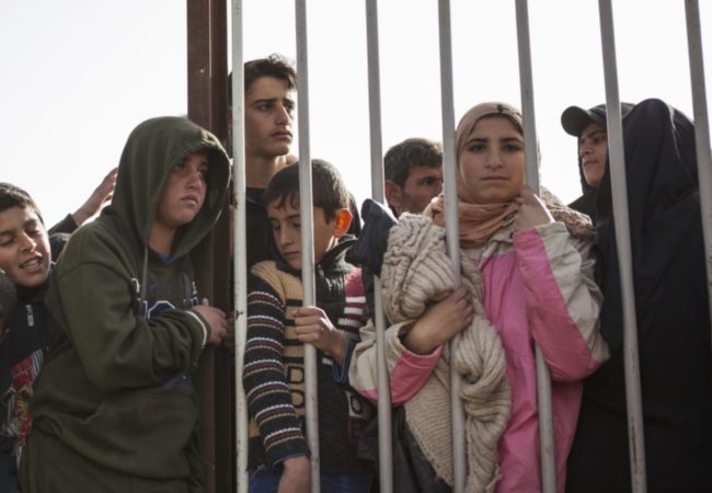 Children peer through the fence during distribution hours in Zaatari refugee camp on January 18, 2016. (Christopher Lee/GroundTruth)