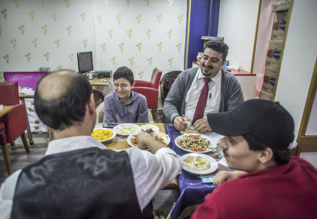 Salloura employees, including head waiter Abu Yazan (top right) sit down for a meal. (Photo by Joris van Gennip/GroundTruth)