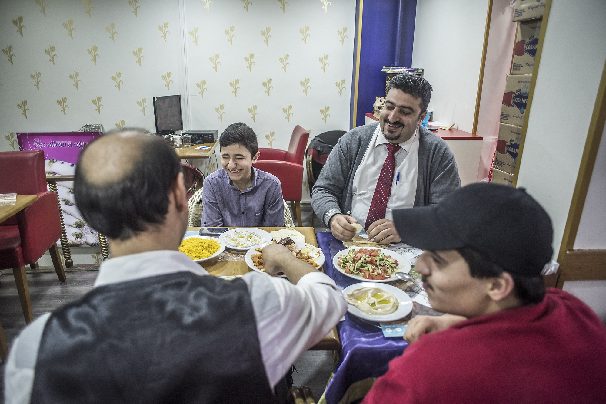 Salloura employees, including head waiter Abu Yazan (top right) sit down for a meal. (Photo by Joris van Gennip/GroundTruth)