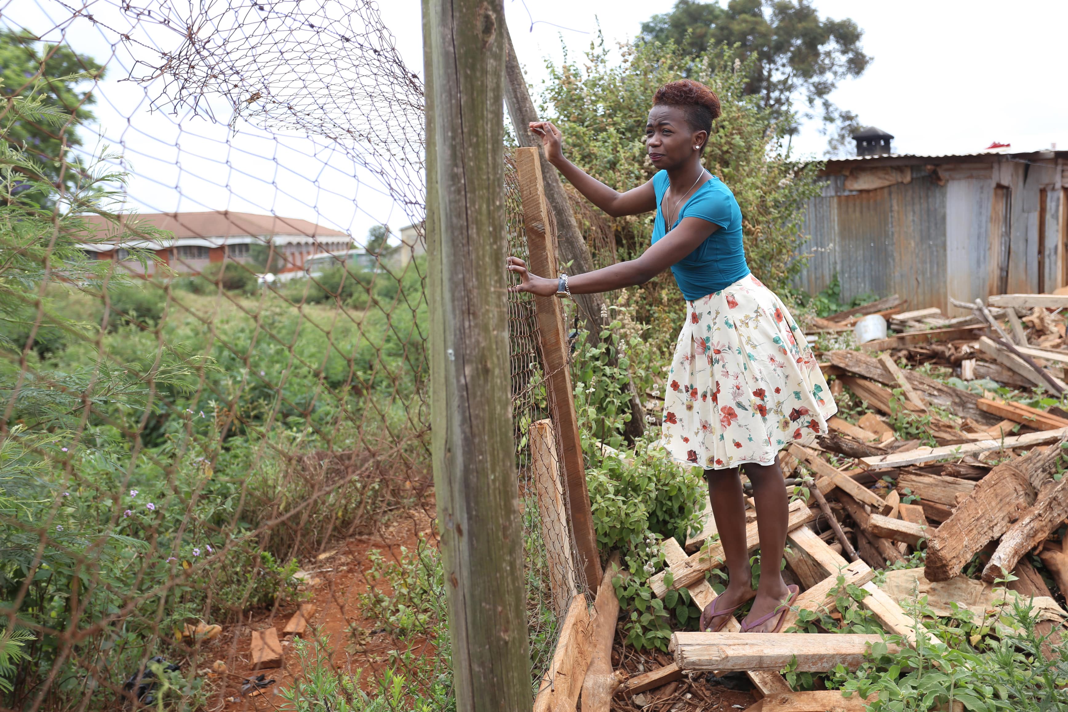 Sandra Gituchu along the perimeter fence of her residence at Moi University. She is among the Garissa University terror attack survivors who transferred to Moi last year. She now obsesses about her escape route in case of another attack by al-Shabaab. (Billy Mutai/GroundTruth)