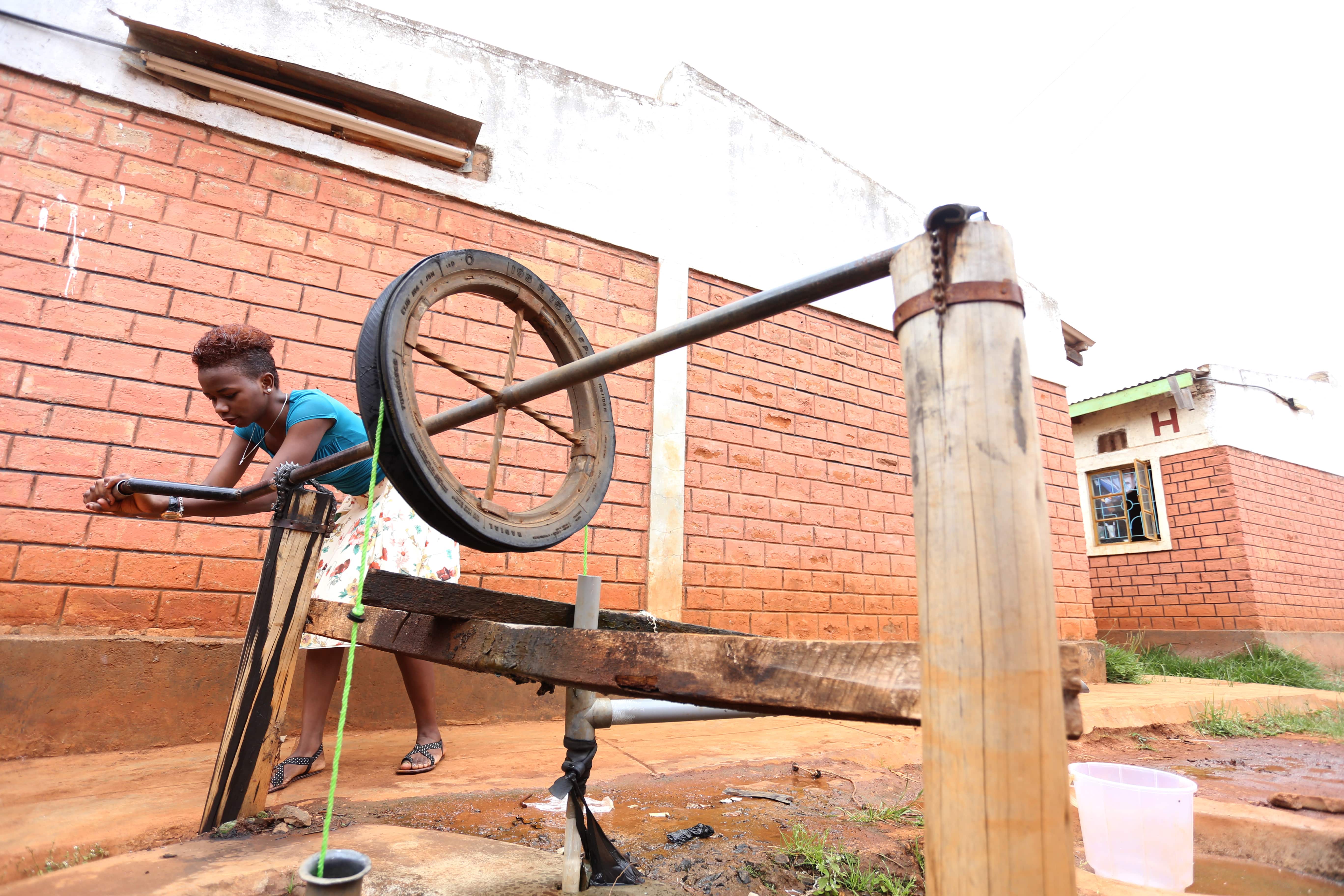 Sandra Gituchu manually fetching water outside a residential houses where she lives with other Moi University students. (Billy Mutai/GroundTruth)