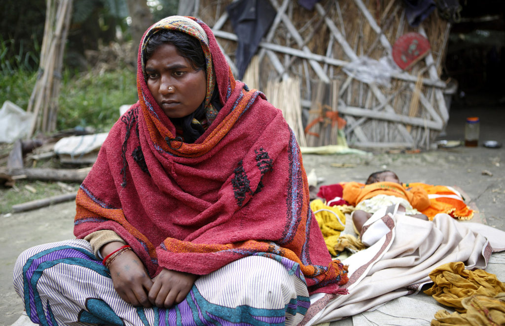 A few days after her sterilization operation, Sonia Devi, 35, recuperates at home with her newborn daughter, Lovely, her fourth child, in the Begusarai District in Bihar. After she gave birth, Sonia says an asha, an accredited social health activist, told her about the option of using sterilization to limit her family size. Sonia didn't appear to be aware of other methods of birth control. (Photo by Sarah Weiser/GroundTruth)