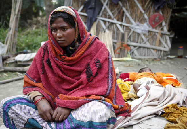 A few days after her sterilization operation, Sonia Devi, 35, recuperates at home with her newborn daughter, Lovely, her fourth child, in the Begusarai District in Bihar. After she gave birth, Sonia says an asha, an accredited social health activist, told her about the option of using sterilization to limit her family size. Sonia didn't appear to be aware of other methods of birth control. (Photo by Sarah Weiser/GroundTruth)