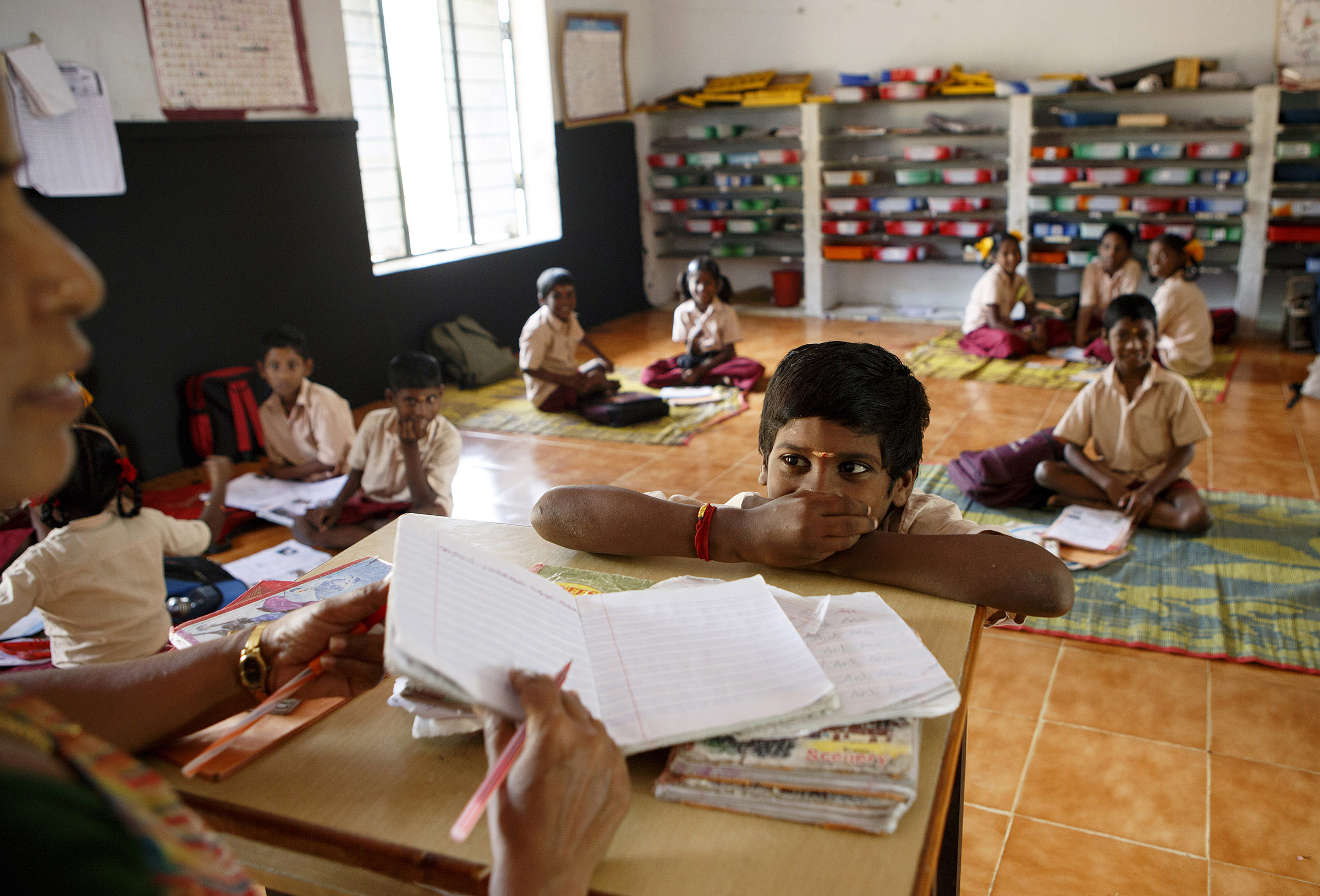 Sanmugam Loganathan looks at his teacher, S. Kanmani, as she reviews his notebook at the Panchayat Union Middle School in the Kancheepuram District of Tamil Nadu, a state in southern India. Literacy rates are much higher in Tamil Nadu and across southern India in general. The state government has used various schemes to improve literacy, including offering free textbooks, uniforms, bus passes and bicycles. The Midday Meal Scheme - a nationwide program that provides free lunches to schoolchildren - was first introduced in Tamil Nadu, and has been particularly effective in improving attendance and childhood nutrition.