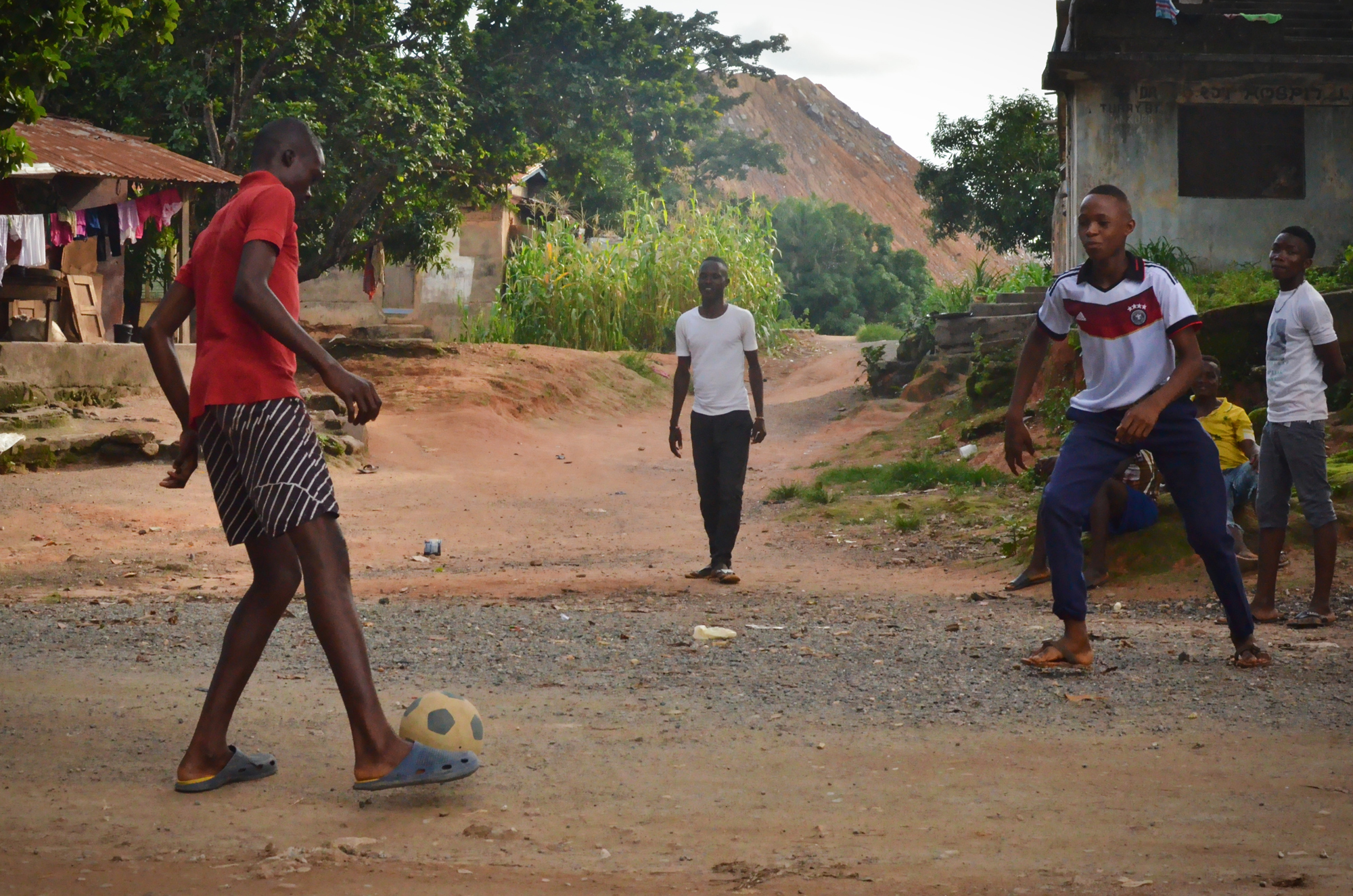 While waiting for the bi-weekly mine blasting to end, young men pass time by playing football at a security checkpoint. Their homes are within the mine's 500-meter "safety zone,” which makes them vulnerable to flying debris.