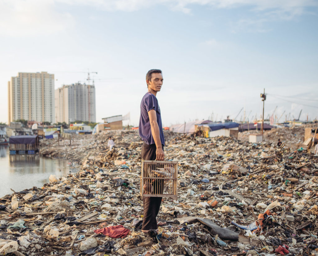 A man with his pigeons poses for a photograph in Pasar Ikan district of North Jakarta. As part of Jakarta's river revitalization project, a settlement in this district was recently razed, leaving its residents homeless. (Photo by Muhammad Fadli/GroundTruth)