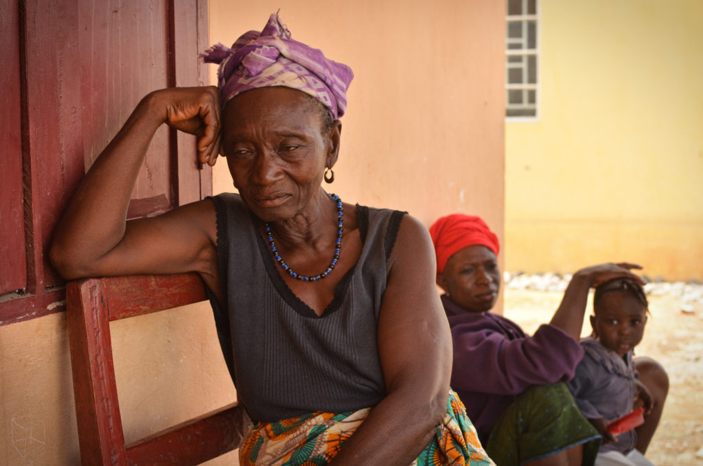 Kumba James, left, and her daughter, Kumba Johnbull, were moved to the resettlement site in 2013 because of diamond mining. The locals locals call the resettlement Benghazi. They say that they are frustrated by limited access to water during the dry season, when the resettlement site’s wells dry up. (Photo by Cooper Inveen/ICIJ)