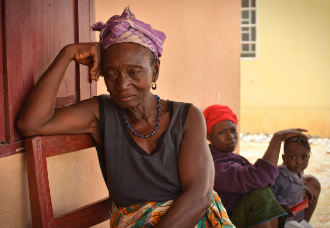 Kumba James, left, and her daughter, Kumba Johnbull, were moved to the resettlement site in 2013 because of diamond mining. The locals locals call the resettlement Benghazi. They say that they are frustrated by limited access to water during the dry season, when the resettlement site’s wells dry up. (Photo by Cooper Inveen/ICIJ)