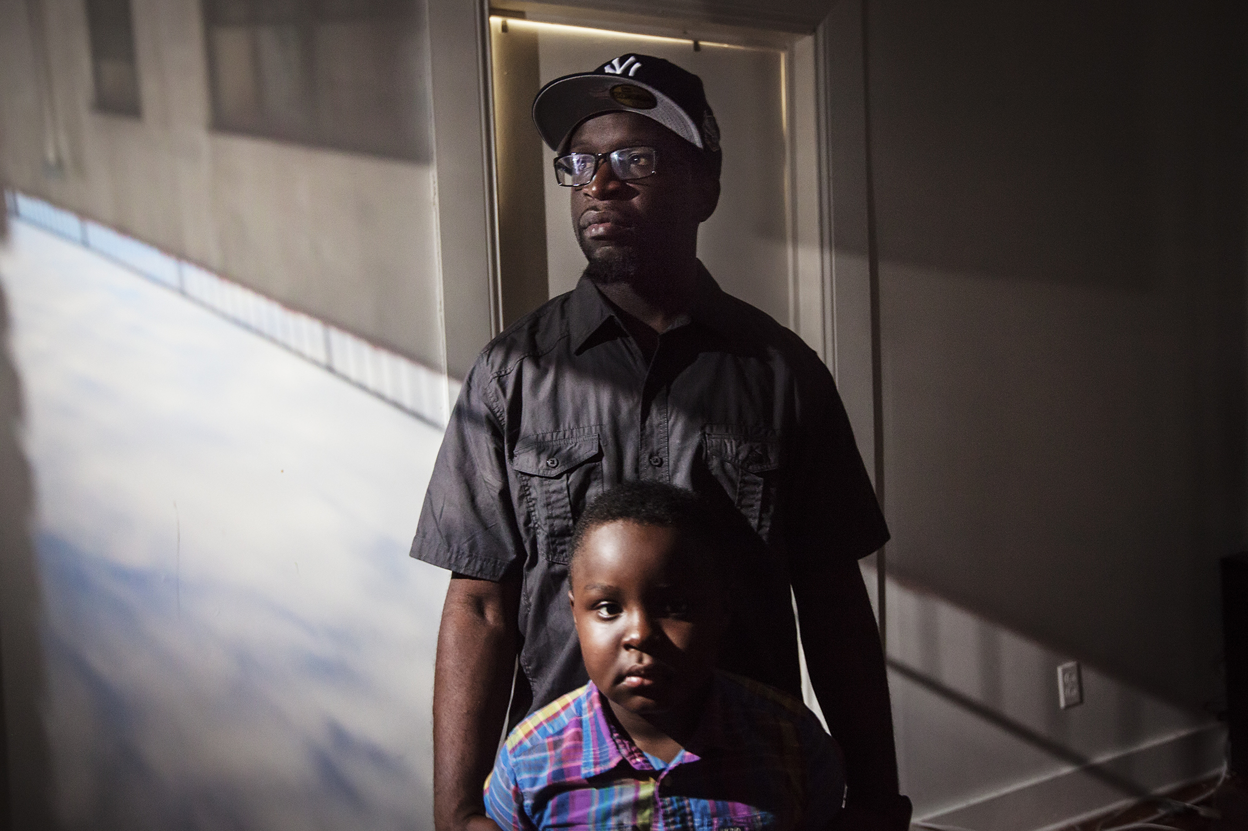 Clifton Jerrick, 35, poses for a portrait with his son, Logan Suttor, in East New York, NY on March 12, 2016. ÒBeing a father is just not a title, itÕs a job. ItÕs a full time job until the day you die.Ó Raising East New York (RENY) is a portraiture project about Black fathers where the photographer, Phyllis B. Dooney, uses a photographic technique called Camera Obscura to project the outside streets into the subjects apartment in real time.
