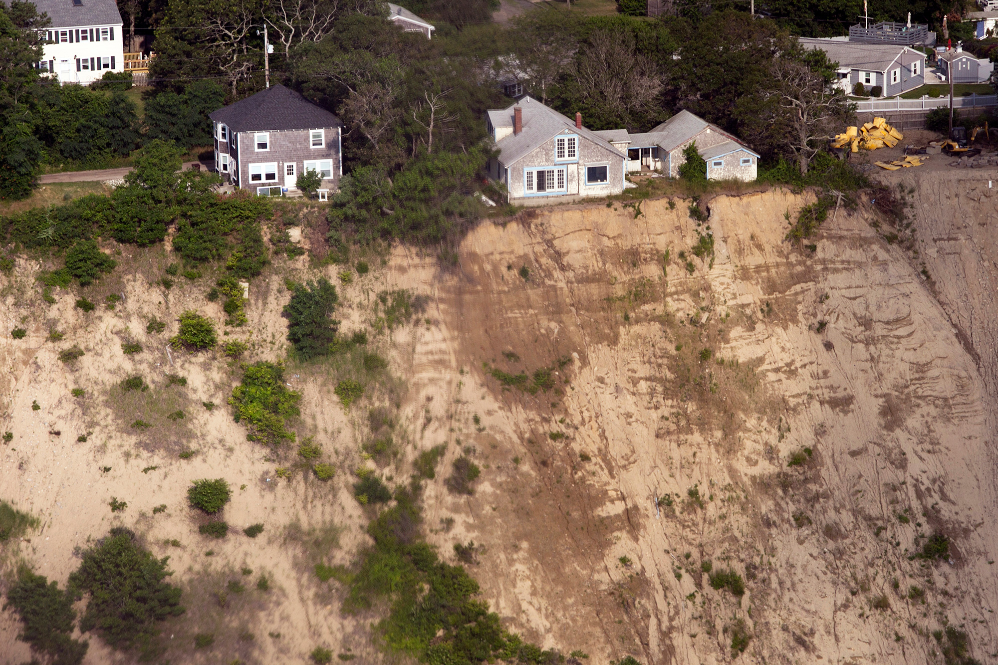 Homes hover dangerously close to the cliff’s edge in Plymouth, on the South Shore of Massachusetts. With up to 68 percent of beaches on the East Coast eroding, some residents are moving out. But many are not budging, choosing instead to bolster their homes and adapt to climate change. (Photo by Lauren Owens Lambert/GroundTruth)