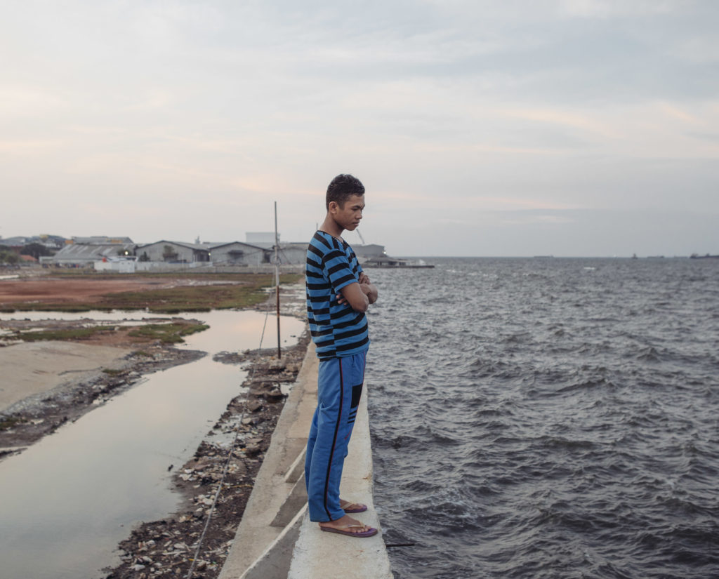 Feri Yadi, a resident of Muara Baru in North Jakarta, stands atop a recently built seawall. He has little confidence it will work as expected. "Like in the past, this will be broken somehow" he said. (Photo by Muhammad Fadli)
