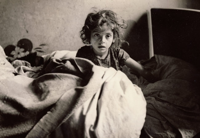 A young female refugee sits up in bed in France, 1940. (Photo by Martha Sharp/Sharp Family Archives)