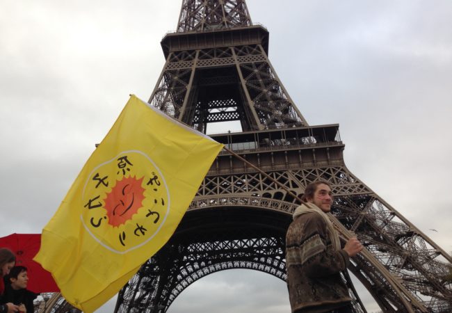 A protestor stood in front of the Eiffel Tower during COP21 in Paris, where 195 countries made climate history, adopting an ambitious and unprecedented international plan to limit global warming to below 2 degrees. (Carlos Felipe Pardo/Flickr)
