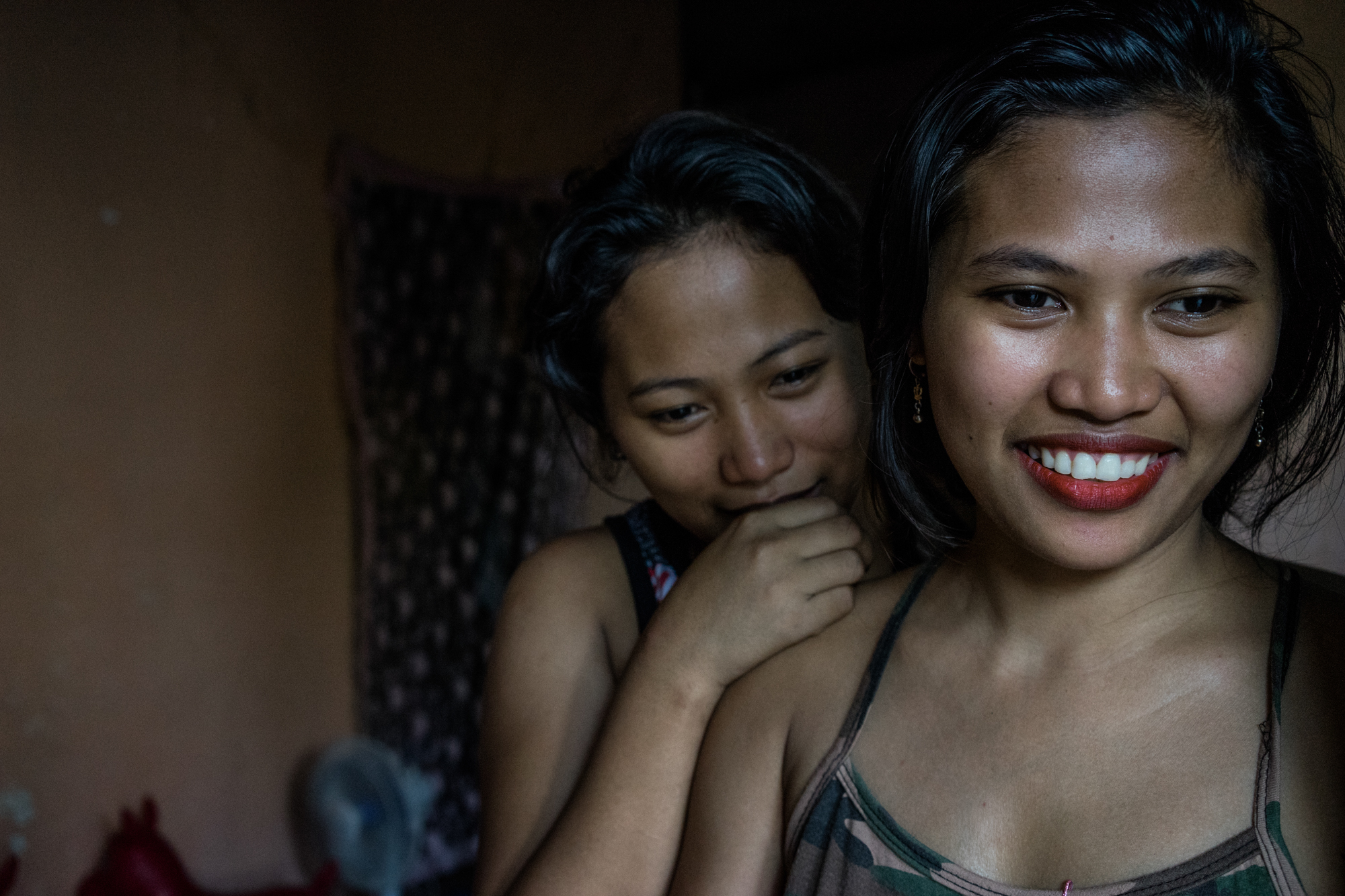 Sisters Gemma (right) and Joanne in their home in Angeles City, which is notorious for its sex industry and its red light district. Shortly after being displaced from Typhoon Ruby, Gemma followed her sister to Angeles to work as a prostitute. (Photo by Hannah Reyes Morales/GroundTruth)