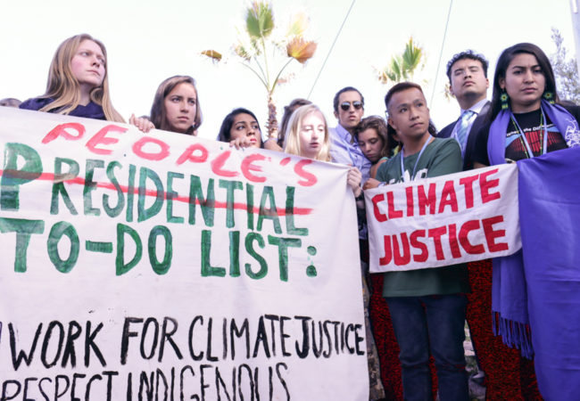 Worried climate justice advocates hold up a to-do list to address climate change and its many effects in lieu of Donald Trump's upcoming U.S. presidency. (Photo by Justine Calma/GroundTruth)