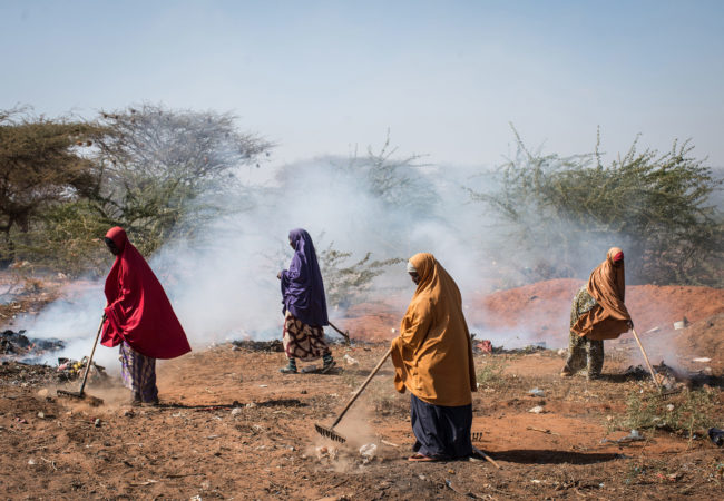 Women burn trash on the roadside in Dadaab refugee camp. In 2011, a severe drought pushed tens of thousands of Somalis from their homes, swelling the camp's population. Host to more than a third of a million people, Dadaab is the world's largest refugee camp, but it's now in danger of being shut down. (Nichole Sobecki/GroundTruth)