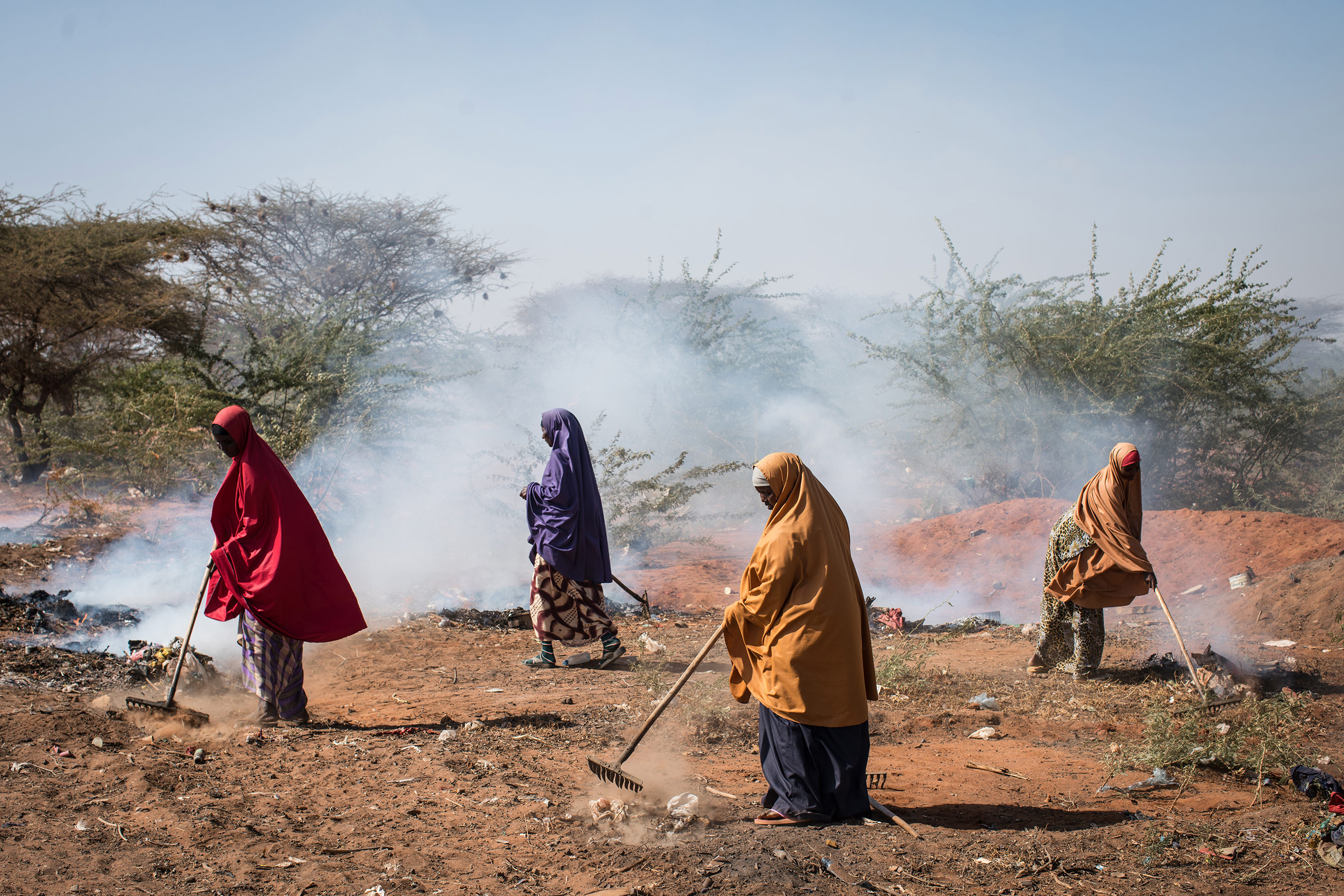 Women burn trash on the roadside in Dadaab refugee camp. In 2011, a severe drought pushed tens of thousands of Somalis from their homes, swelling the camp's population. Host to more than a third of a million people, Dadaab is the world's largest refugee camp, but it's now in danger of being shut down. (Nichole Sobecki/GroundTruth)