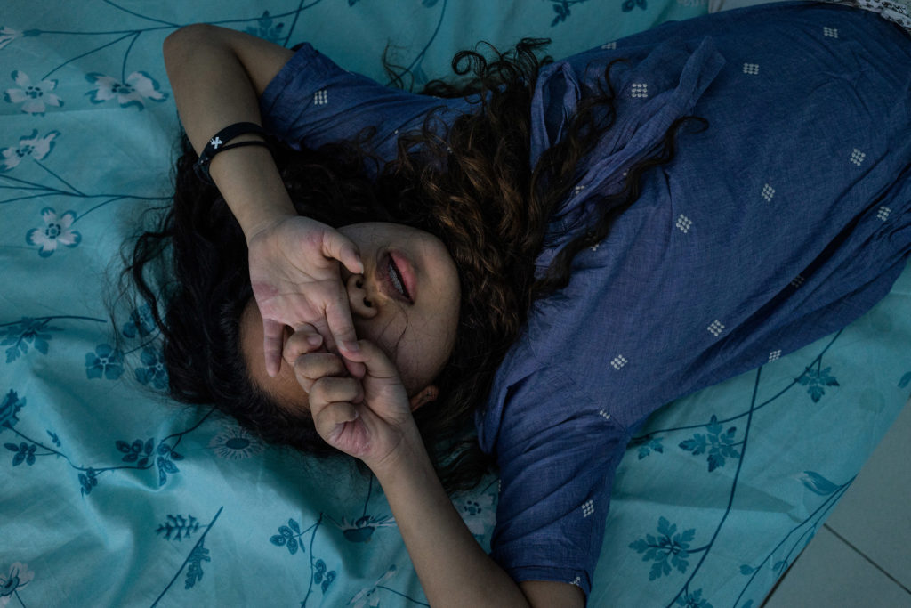A young girl prays in a room in a halfway house outside of Manila. In the wake of typhoons, women and girls from climate change-vulnerable areas, particularly Samar and Leyte, wind up in the sex trade after being displaced from storms. Young girls who are rescued from sex trafficking and prostitution enter halfway houses for rehabilitation, legal counseling and, for some, schooling. (Hannah Reyes Morales/GroundTruth)