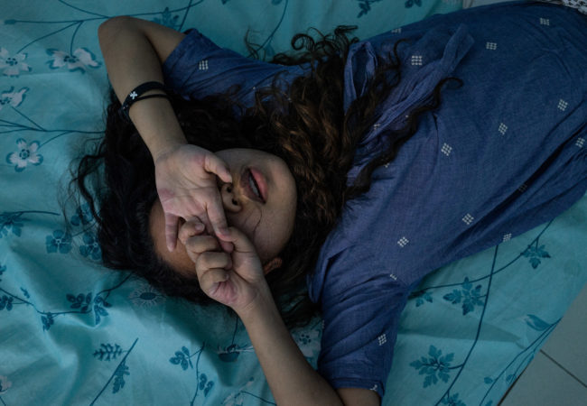 A young girl prays in a room in a halfway house outside of Manila. In the wake of typhoons, women and girls from climate change-vulnerable areas, particularly Samar and Leyte, wind up in the sex trade after being displaced from storms. Young girls who are rescued from sex trafficking and prostitution enter halfway houses for rehabilitation, legal counseling and, for some, schooling. (Hannah Reyes Morales/GroundTruth)