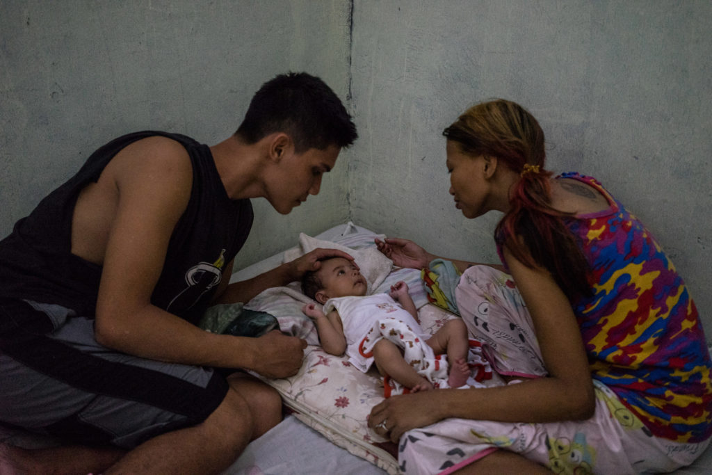 Filipina sex worker Jojo and her husband dote on their baby in their home in Angeles City, notorious for its red light district. In the wake of storms many women from climate change vulnerable areas move to Angeles City to enter the sex trade after having been displaced. (Hannah Reyes Morales/GroundTruth)