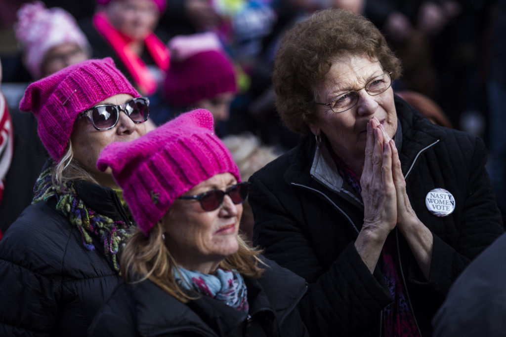 Mille Wrench, 72, of Kalamazoo, Mich., listens to speakers during the Women's March on Lansing outside of the Michigan State Capitol Building in Lansing, Mich., on Saturday, January 21, 2017. (Photo by Brittany Greeson/GroundTruth)