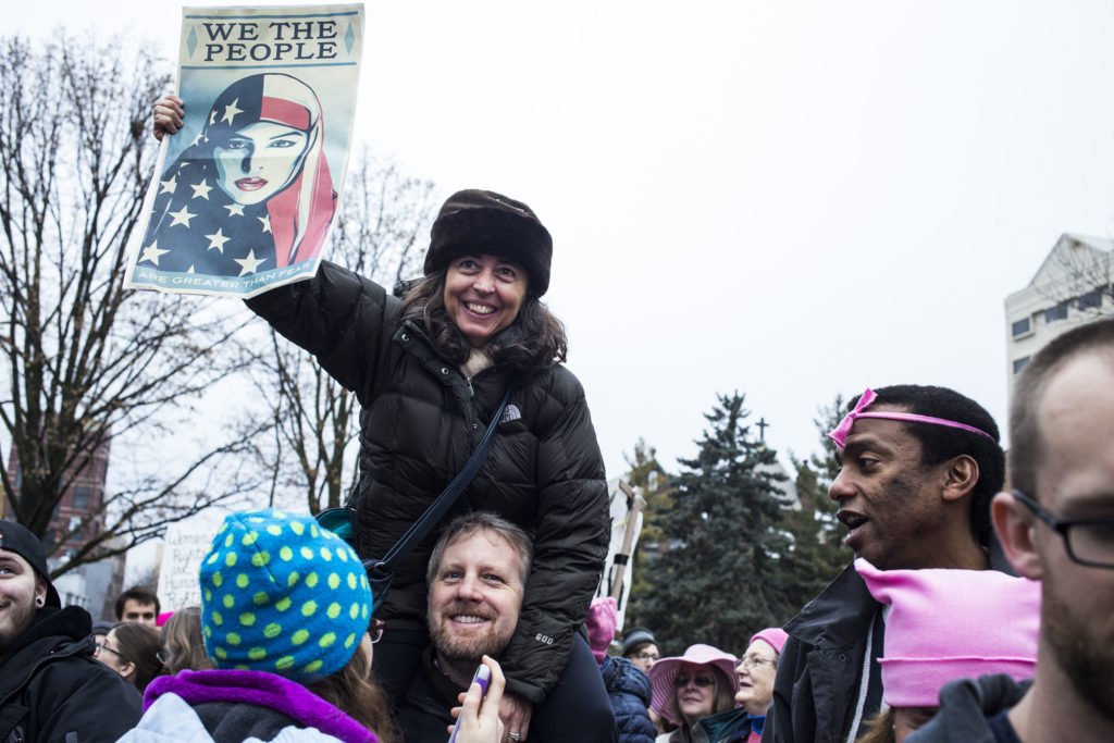 Monica Silva, 49, of East Lansing, Mich., sits on her husband's shoulders during the Women's March on Lansing outside of the Michigan State Capitol Building in Lansing, Mich., on Saturday, January 21, 2017. (Photo by Brittany Greeson/GroundTruth)