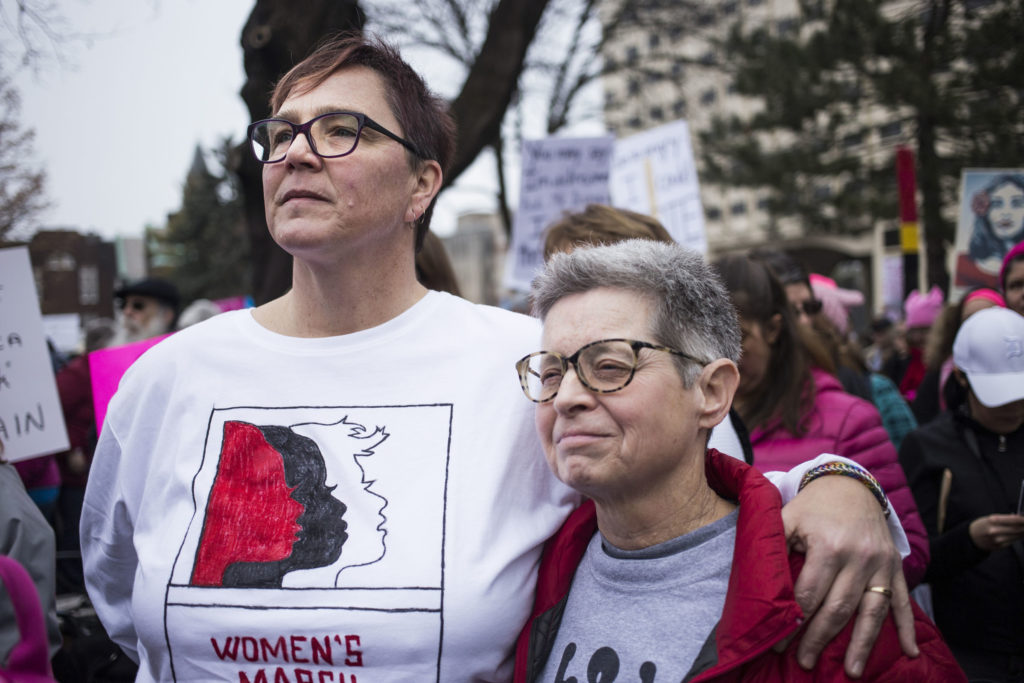 Lisa Mapp, 54, and marital partner, Chris Smith, 44, of Mason, Mich., embrace while listening to speakers during the Women's March on Lansing outside of the Michigan State Capitol Building in Lansing, Mich., on Saturday, January 21, 2017. The pair said they came to the march in hopes of taking power back, rather than feeling powerless. "It's really wonderful seeing this many people," Smith said. (Photo by Brittany Greeson/GroundTruth)