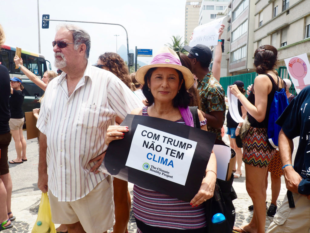 A demonstrator in Rio holds a sign that says "With Trump, there's no climate." (Photo by Catherine Osborn/GroundTruth)