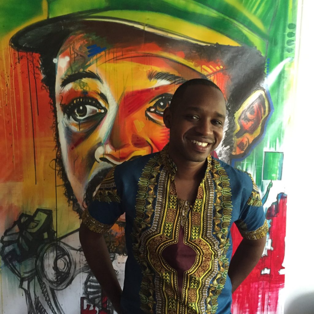 Boniface Mwangi stands in front of a painting in PAWA254, an artspace and office.