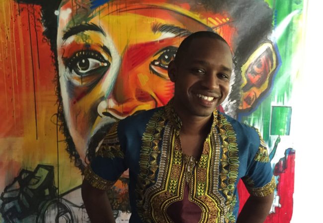 Boniface Mwangi stands in front of a painting in PAWA254, an artspace and office.