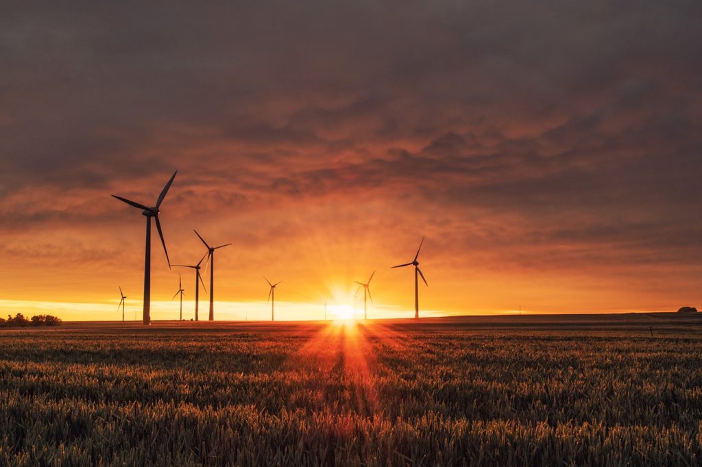 Wind turbines spin through sunset hours (Photo via Creative Commons).