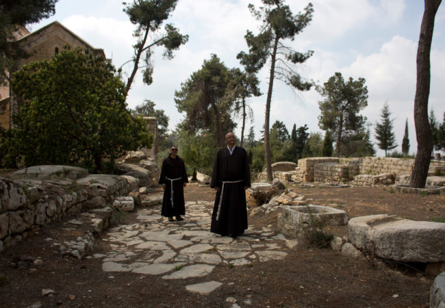 Father Salem Yunis, from Aleppo, Syria, and Father Oscar Rodriguez, from El Salvador, stand on the remnants of an ancient Roman road in Emmaus, which today lies in West Bank territory. (Photo by Heidi Levine/GroundTruth)