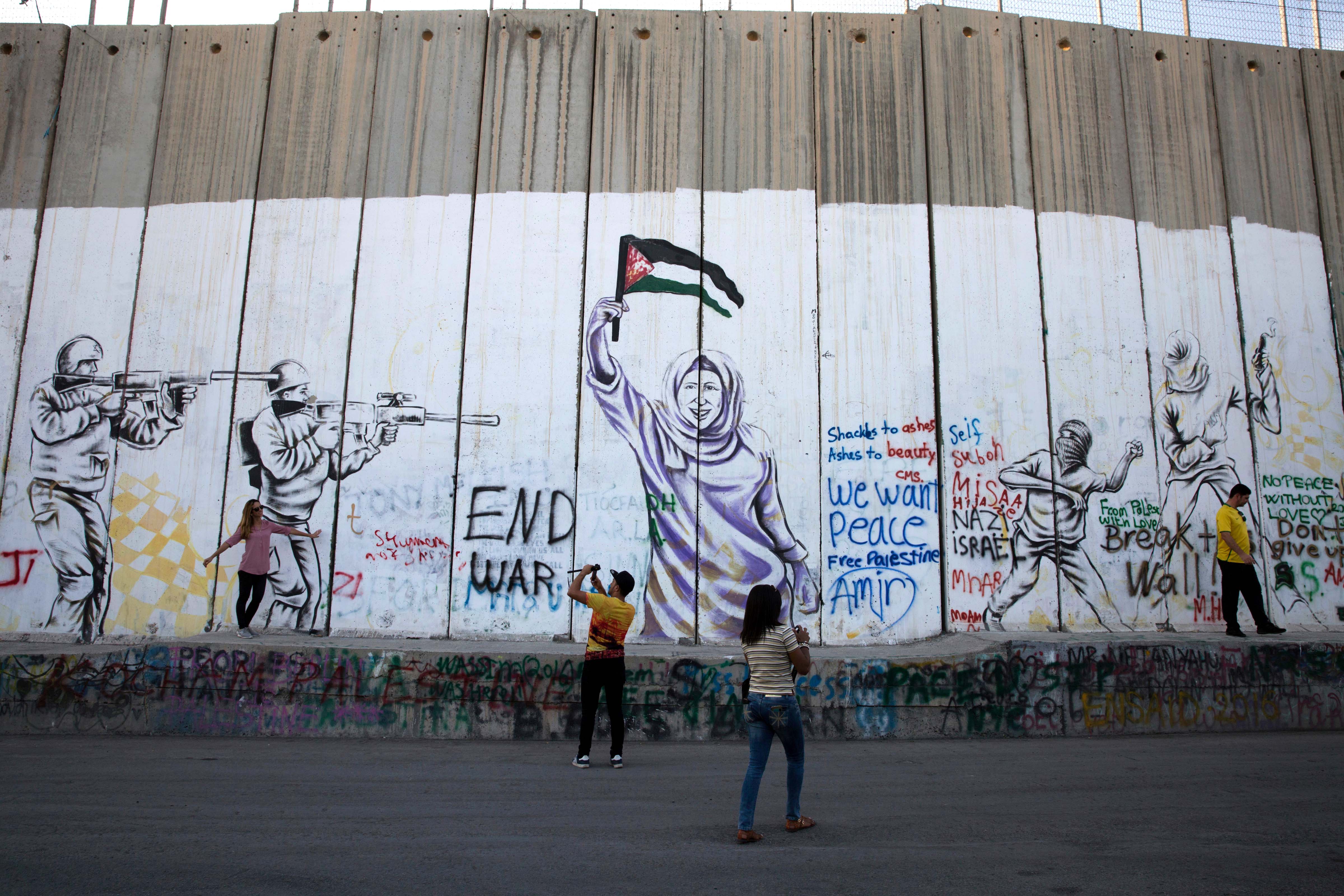 Tourists from Brazil visit the 8-meter-high concrete separation wall in the Palestinian city of Bethlehem. Israel's separation barrier has become an attraction for tourists from all over the world. (Photo by Heidi Levine)