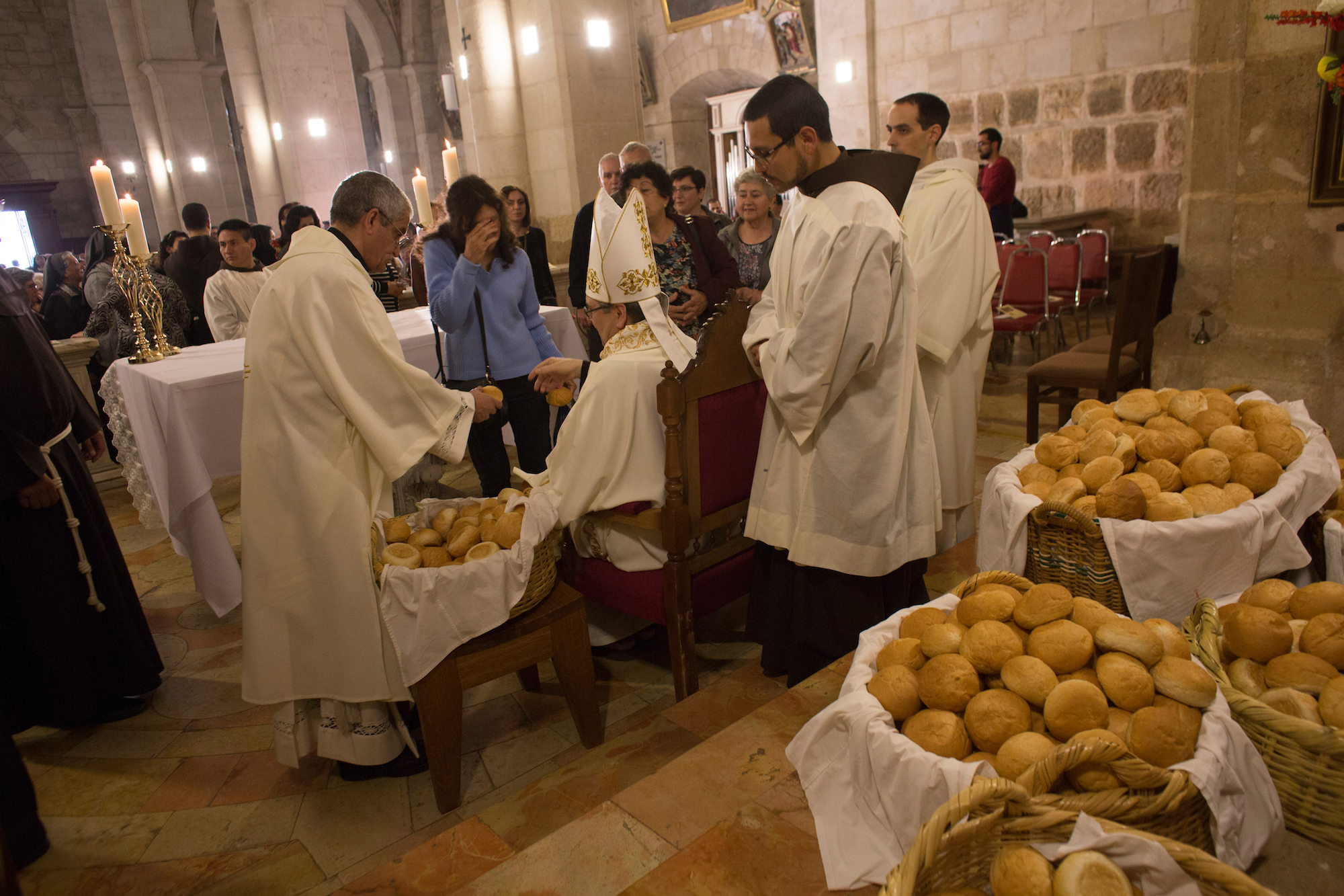 Christian clergymen hand out rolls of bread to worshippers, a tradition in Christian Masses. Over a thousand Christians from the West Bank, Jerusalem and other countries attended the Mass at the Franciscan Church of Emmaus in the West Bank village of El Qubeibehon on Monday, April 17, 2017. (Photo by Heidi Levine/GroundTruth)