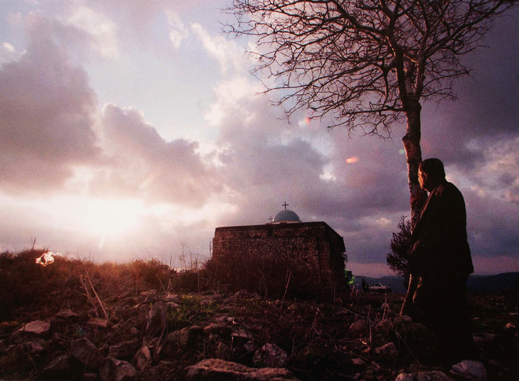 Elias Khoury, a Christian Arab, gazes at the stone church in the Palestinian village of Ikrit, where he was born. Residents were forced out of the village by Israeli soldiers during the 1948 Arab-Israeli war. On Christmas, they still attend services at the old stone church. Ikrit, December 1998 (Photo by Heidi Levine/GroundTruth)