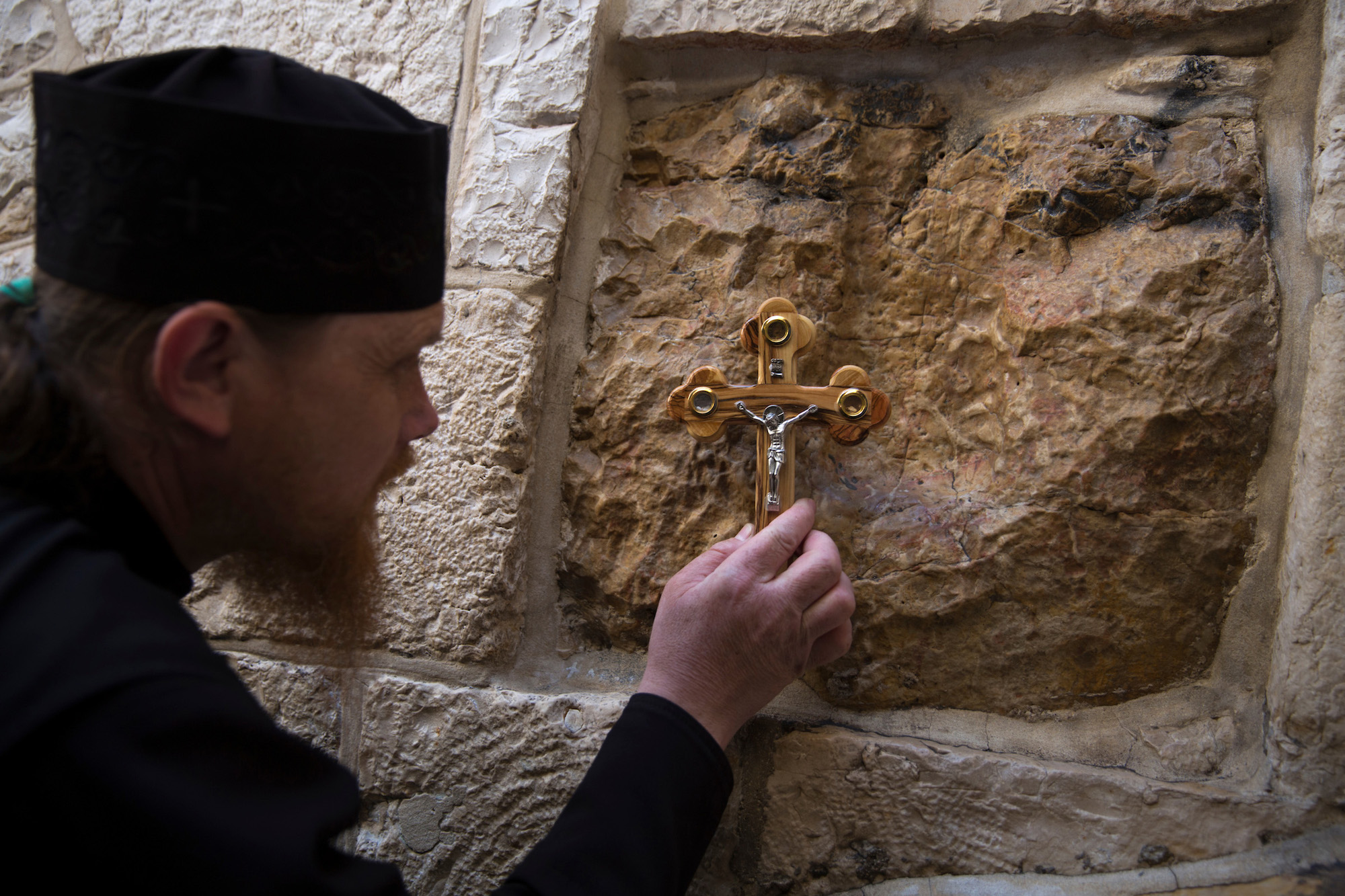 An Orthodox Christian worshipper stops at one of the fourteen stations of the cross along the Via Dolorosa, or “Way of Sorrow”, in the Old City of Jerusalem. On Good Friday, Christians around carry out a procession along the Via Dolorosa, which is believed to be the path that Jesus walked on the way to his crucifixion. Jerusalem, April 14, 2017. (Photo by Heidi Levine/GroundTruth)