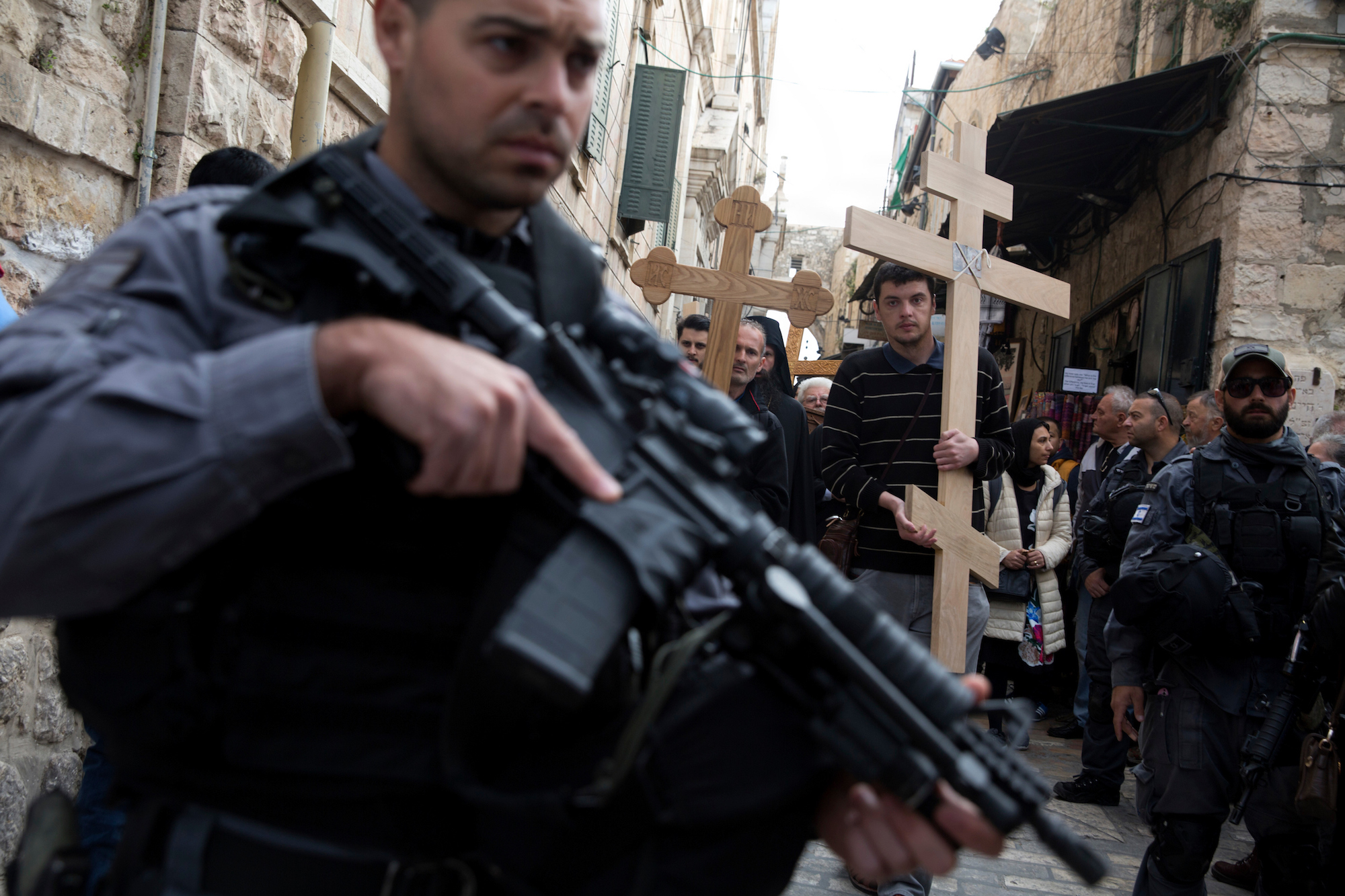 Israeli border police stand guard as Christian pilgrims from Serbia carry wooden crosses along Via Dolorosa, or “The Way of Sorrow" in the Old City of Jerusalem on April 14, 2017. Security was heightened in and around the Old City on Friday and through the Easter weekend after a 20-year-old British exchange student in Jerusalem was killed Friday in a stabbing attack, the latest in a reported wave of attacks by Palestinian militants that have taken the lives of 40 Israelis and two foreigners over the last 18 months. (Photo by Heidi Levine/GroundTruth).