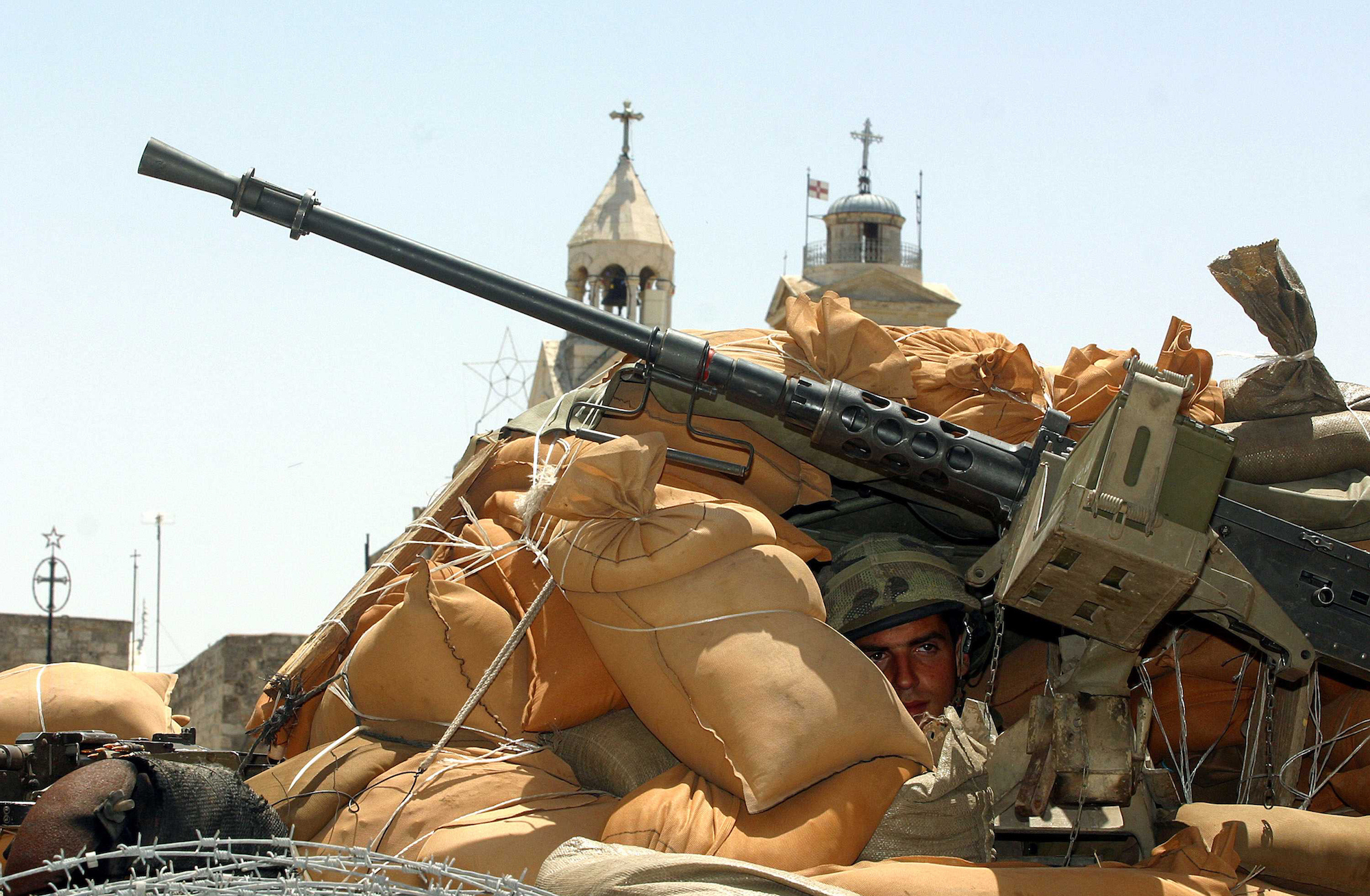 An Israeli soldier in an armored personnel carrier in front of the Church of Nativity in the biblical city of Bethlehem, where the Christian faith holds that Jesus Christ was born. Israeli forces entered the city in May 2002 in a wide-scale operation to arrest Palestinian militants. Bethlehem, May 2002 (Photo by Heidi Levine)