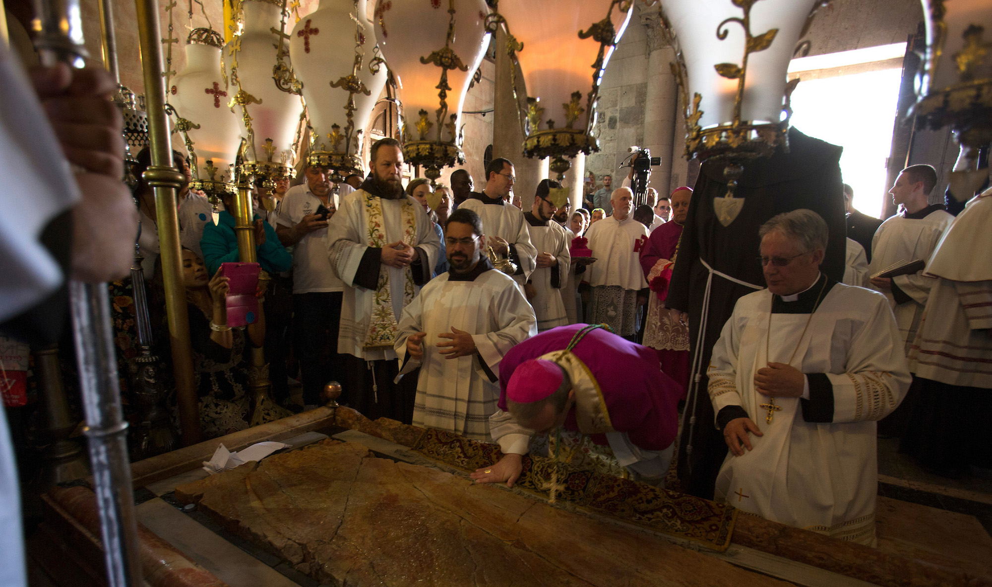Latin Patriarch of Jerusalem, Pierbattista Pizzaballa (wearing pink), and other clergymen stand by the Stone of Unction during the Easter Sunday procession at the Church of the Holy Sepulchre, which is believed to be the site of the crucifixion and burial of Jesus Christ. Thousands of Christians from around the world flocked to Jerusalem to commemorate the day when, according to Christian tradition, Jesus resurrected. Jerusalem, April 16, 2017 (Photo by Heidi Levine/GroundTruth).