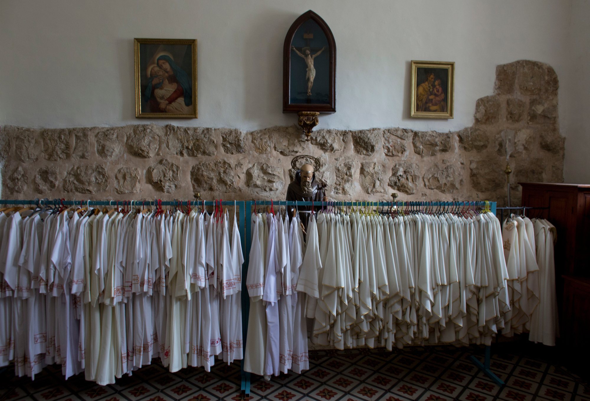 Priestly robes and a statue of Saint Francis are seen in the sacristy of the Franciscan Church of Emmaus in the West Bank village of El Qubeibeh, also known as Emmaus. On Monday April 17, 2017, over a thousand Christian pilgrims flocked to a Mass that celebrates the biblical story of The Road to Emmaus. (Photo by Heidi Levine/GroundTruth)