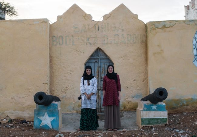 GroundTruth fellows Nichole Sobecki (left) and Laura Heaton (right) stand between two cannons on their reporting trip to Somalia, where they documented links between drought and violent conflict.