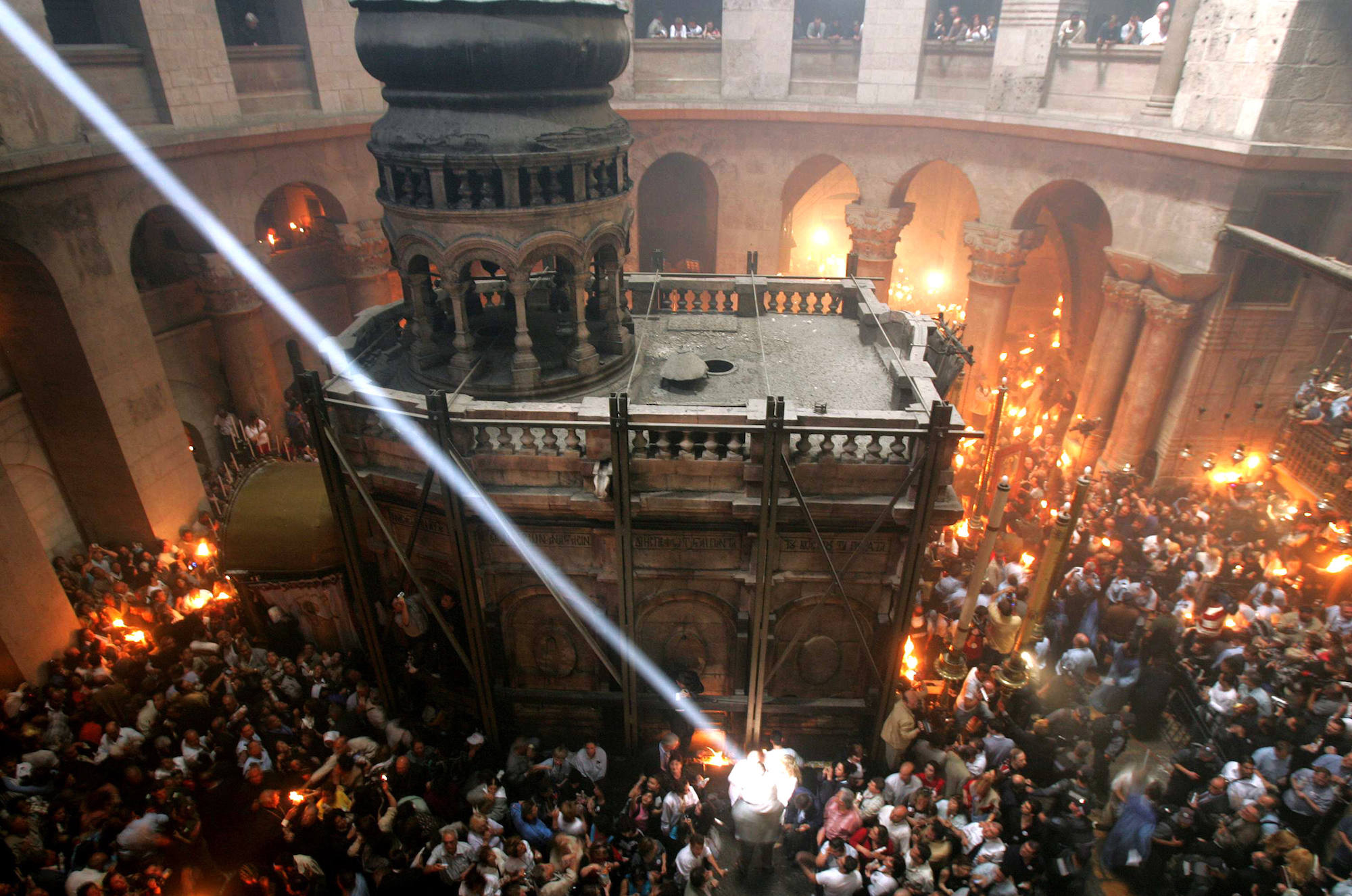 A single shaft of sunlight streams into the Church of the Holy Sepulchre, illuminating the spot where fire erupted from the Tomb of Christ during the ceremony of the Holy Fire on Saturday, the day before Orthodox Christian Easter, in 2005. Fire comes from within the tomb and is quickly spread to candles held by the faithful of Greek Orthodox, Armenian and Coptic denominations. More than 10,000 Orthodox pilgrims filled the church that year. Jerusalem, April 30, 2005 (Photo by Heidi Levine/Sipa Press).