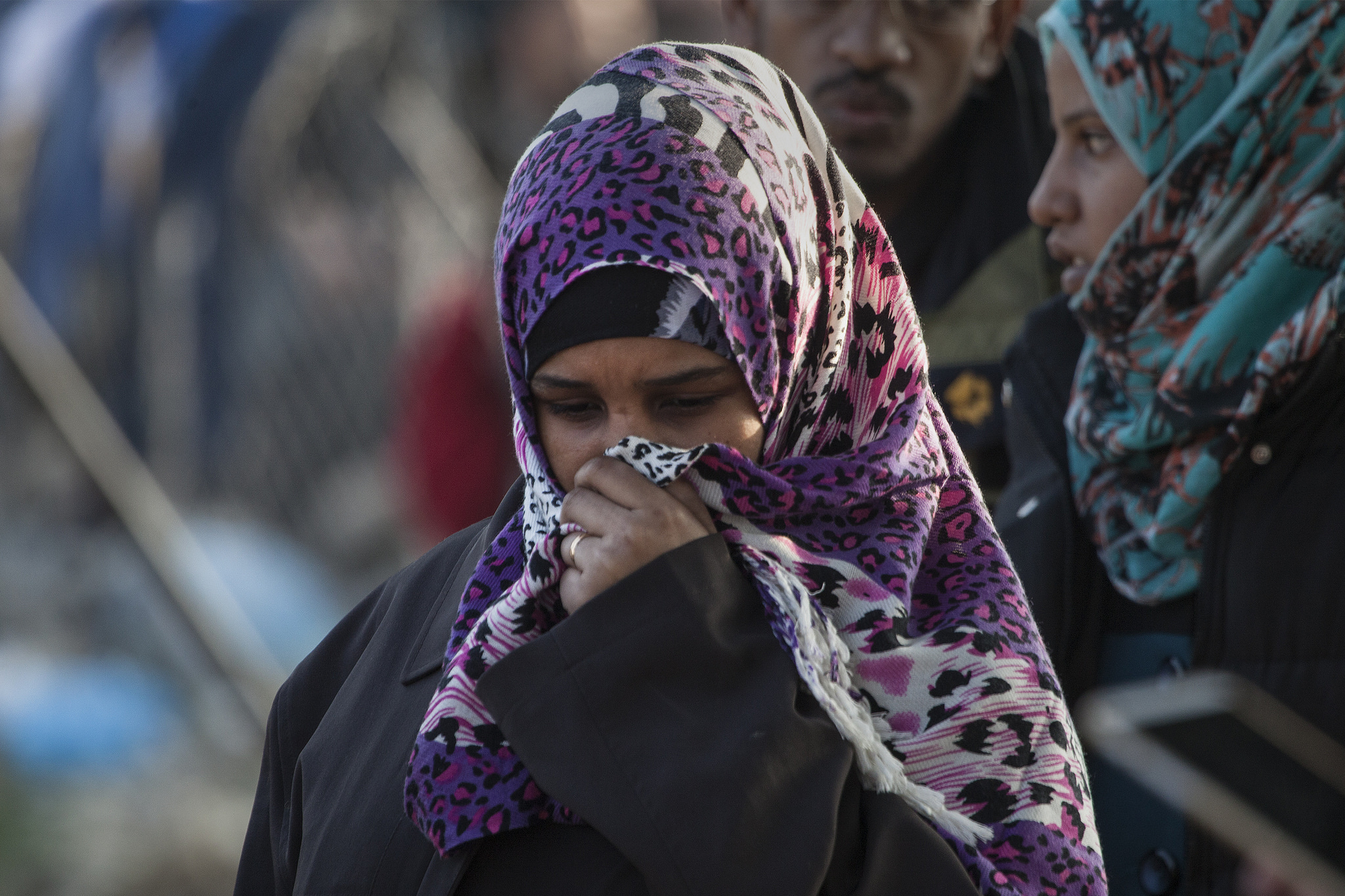 A woman stands and covers her face in Greece among a crowd of other refugees. (Photo by Steve Evans/Flickr Creative Commons)