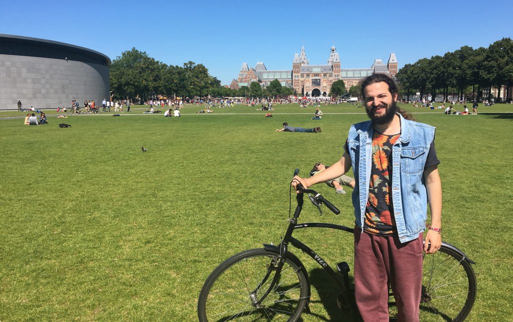 Ahmad Naffory poses with his bicycle in front of the Rijksmuseum in Amsterdam. He fled his native Syria four years earlier after the secret police came to his family's home. He settled as a refugee in Lebanon and pursued music. But after traveling to a music festival, he was denied re-entry into Lebanon and sought asylum in the Netherlands. (Jahd Khalil/GroundTruth)