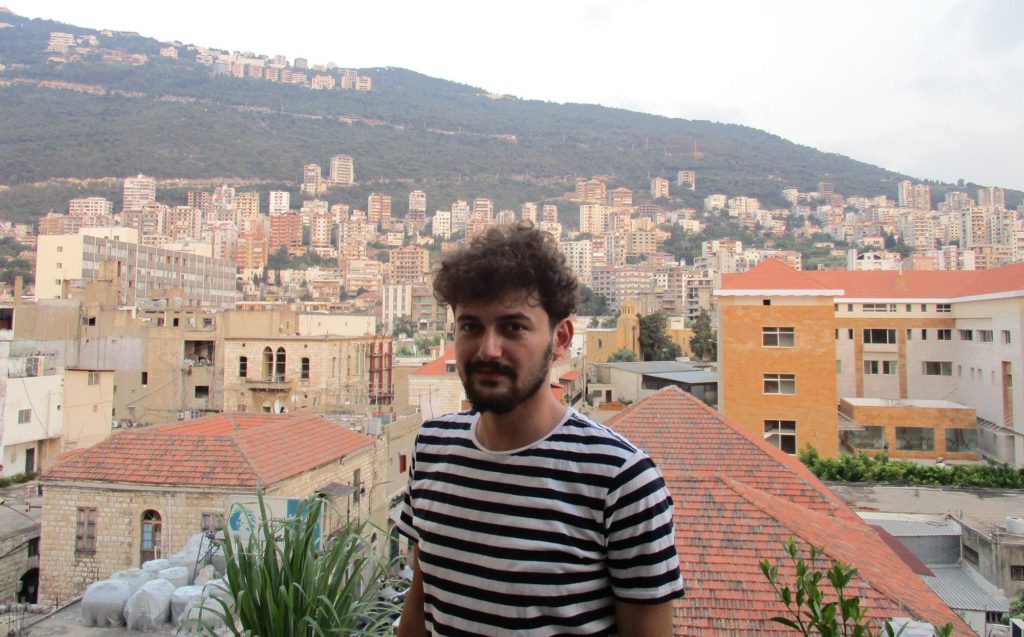 Assa'aleek's Sam Abdullah at sunset in his studio in Jounieh, north of Beirut. Jounieh is a resort town whose hotels have seen a boom in occupancy by Syrians. Sam's hotel is by the ocean, but his own room faces the mountains. He says the ocean creeps him out, after so many Syrians have died in the Mediterranean crossing to Europe. (Jahd Khalil/GroundTruth)